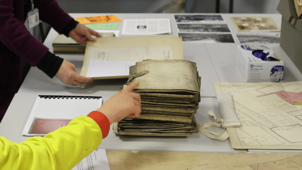 hand pointing at manuscripts on a table